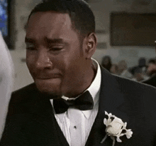 a man in a suit and bow tie is crying at a wedding .