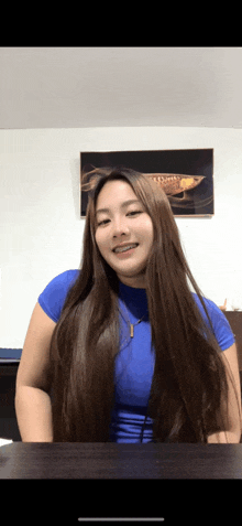 a woman with long hair is sitting at a table in front of a painting