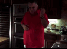 a man in a red shirt is dancing in the kitchen