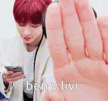 a man with red hair is holding a cell phone and says ben y livi on the bottom
