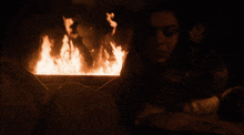 a woman is sitting in front of a fire