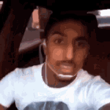 a man wearing headphones is sitting in a car and making a funny face .