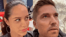 a man and a woman are standing next to each other and looking at the camera .