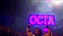 a man holds up a sign that says octa on it