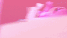 a doll is standing in front of a pink and purple object
