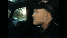 a man wearing sunglasses is driving a car and looking out the window