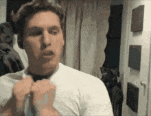 a man in a white shirt adjusts his tie