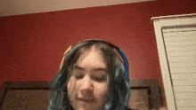 a girl with blue hair is wearing headphones and making a face