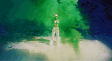 a woman in a bikini and white pants is dancing in front of a green smoke bomb