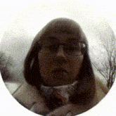 a woman wearing glasses and a scarf looks at the camera in a circle