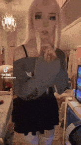 a girl with pink hair is standing in a room in front of a tv holding a banana .