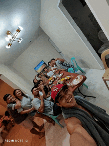 a group of people posing for a picture with a redmi note 13 in the corner