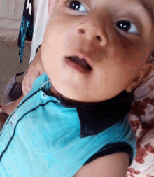 a close up of a baby 's face with a blue shirt