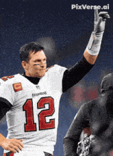 a man wearing a buccaneers jersey holds his hand up in the air