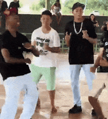 a group of men are dancing in a room with a woman sitting on a bench in the background