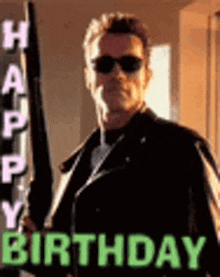 a man wearing sunglasses and a leather jacket is holding a gun in front of a sign that says `` happy birthday '' .