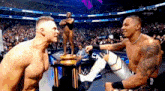 two wrestlers are standing next to each other in front of a trophy in a stadium ..