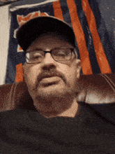 a man wearing glasses and a hat is sitting in front of a chicago bears flag