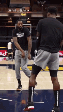 a man wearing a shirt that says brooklyn is standing on a basketball court