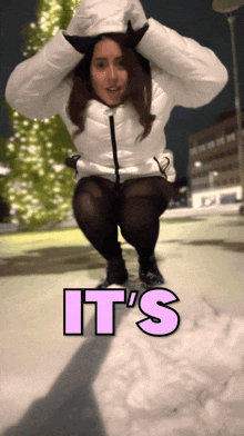 a woman in a white jacket is squatting in the snow with the words it 's written above her