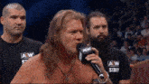 a wrestler is talking into a microphone that says aew staff on it