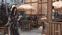 a woman wearing a hat and sunglasses is standing in front of a bar with abc written on it