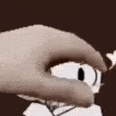 a hand is holding a cartoon character 's eye in a close up .