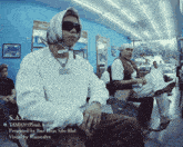 a man with a scarf around his head is sitting in a chair in a barber shop