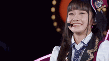 a girl with a microphone in her mouth smiles in a dark room