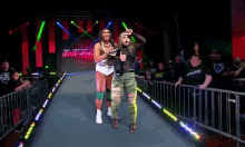 two female wrestlers are walking down a ramp that says impal