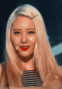 a woman with blonde hair and red lips is wearing a striped top