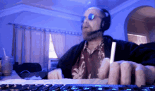 a man wearing headphones and sunglasses is typing on a computer keyboard
