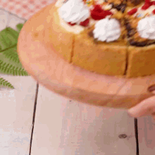 a person is holding a cake with whipped cream and sprinkles on top