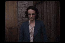 a man in a suit and glasses is talking about ghosts confidently .