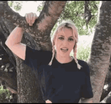 a woman with pigtails is standing next to a tree