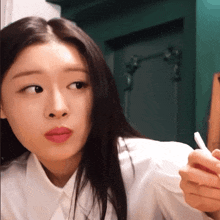 a woman with long black hair wearing a white shirt is holding a pencil