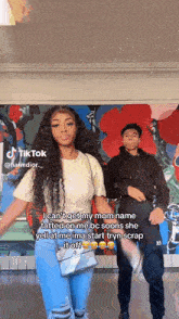 a man and a woman are dancing in front of a wall that has graffiti on it .