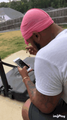 a man with a pink headband is looking at his phone