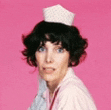 a woman wearing a chef 's hat is standing in front of a pink wall .