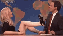 a man and a woman are sitting at a table with a woman 's leg on the man 's lap .