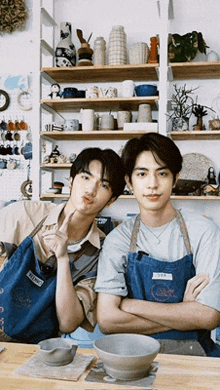 two men wearing aprons are standing next to each other in a room
