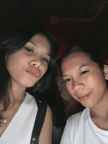 two women are posing for a picture and one is wearing a white top