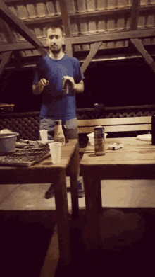 a man in a blue shirt stands in front of a table
