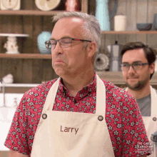 a man wearing an apron with the name larry on it is making a funny face .