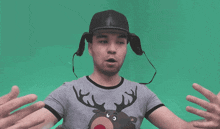 a man wearing a hat and a reindeer shirt reaches out his arms