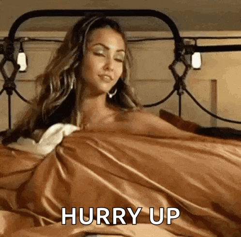 a woman is laying in bed with a brown blanket and a brown blanket .
