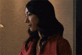 a woman in a red coat stands in front of a wall