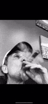 a man with a hat is smoking a cigar in a black and white photo .