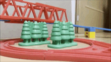 a toy train set with trees and a bridge