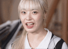 a woman with blonde hair is smiling and wearing a black and white vest